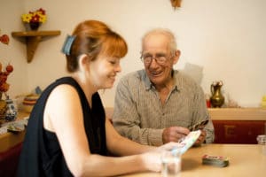 Betreuerin spielt Karten mit Patient