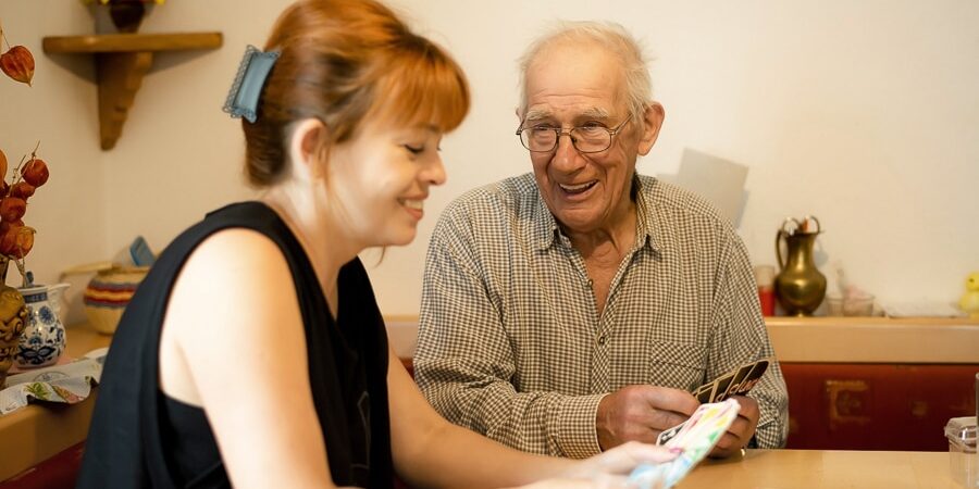 Betreuerin spielt Karten mit Patient